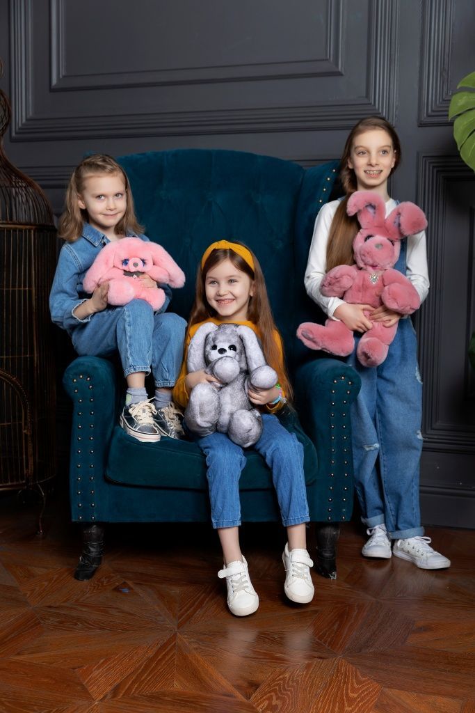 На фото большие игрушки зайцы из натурального меха на руках 3 девочек